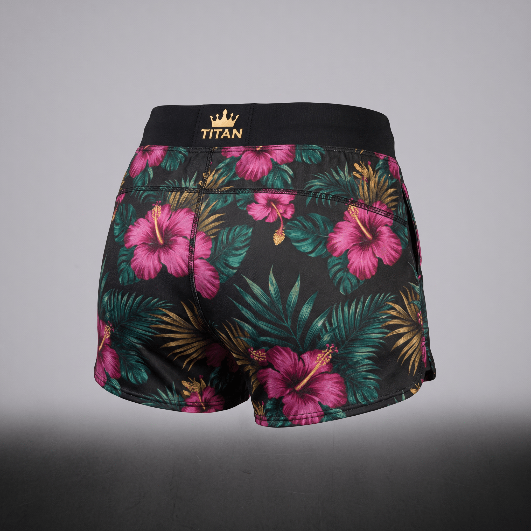 Back view of black athletic shorts with pink floral tropical print and gold Titan crown logo waistband.