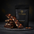 TITAN Keto Chocolate Bark Almond & Sea Salt — dramatic shattered bark shot with roasted almonds and Himalayan sea salt crystals on dark slate