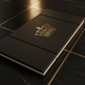 Black folding gymnastics mat with a gold crown logo on a matching black marble floor with gold inlay lines.