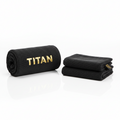 Black XL gym towel by TITAN with metallic gold logo, featuring one rolled towel and one folded on a white surface.