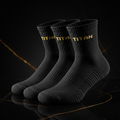 Three black TITAN performance running socks with gold-stitched branding on ribbed cuffs, set on a marble surface.