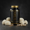 Black supplement bottle with gold label "TITAN Shaggy Mane Mushrooms," surrounded by shaggy mane mushrooms and capsules.