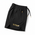 Black TITAN performance shorts with gold logo, side zip pocket, drawstring waist, and vented hem on a white background.